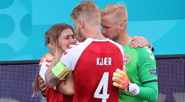 Pemain Denmark, Kasper Schmeichel (kanan) dan Simon Kjaer (tengah) menghibur Sabrina Kvist Jensen, kekasih gelandang Denmark, Christian Eriksen setelah pingsan di lapangan pada laga Denmark vs Finlandia di Grup B Euro 2020 di Parken Stadium, Copenhagen, Sabtu (12/6/2021). (WOLFGANG RATTAY/AFP/POOL)