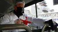 Staf menyemprotkan cairan disinfektan pada pegangan bus di sebuah terminal bus di ibu kota China, 3 Februari 2020. Beijing Public Transport Corporation melakukan pengukuran suhu tubuh karyawan dan memastikan mereka bekerja dengan masker untuk mencegah penyebaran virus corona. (Xinhua/Ren Chao)