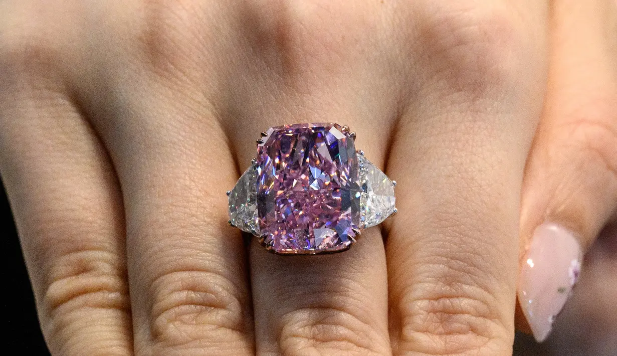 Seorang perempuan memamerkan berlian Sakura 15,81 karat selama pratinjau pra-lelang Christies di Hong Kong pada 20 Mei 2021. Dengan ukuran hampir delapan puluh kali lipat, Sakura juga dapat memecahkan rekor berlian ungu-merah muda termahal untuk dijual di lelang. (Anthony WALLACE/AFP)