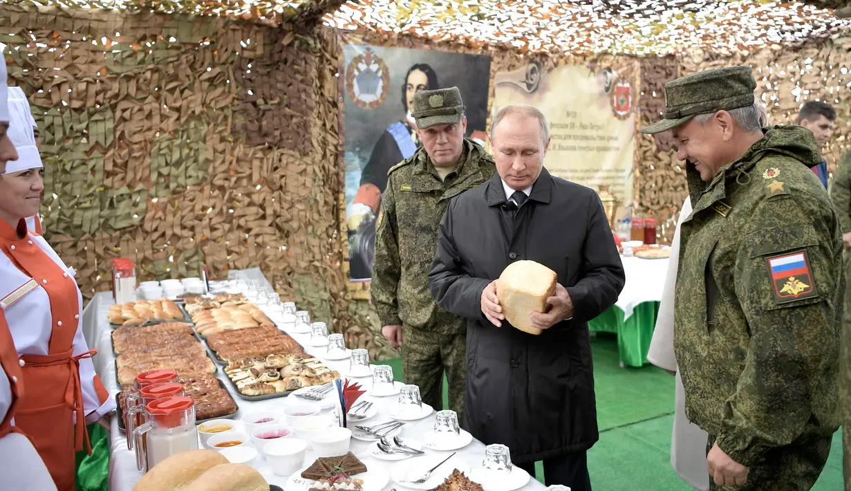 Presiden Rusia Vladimir Putin memeriksa makanan prajurit saat memantau latihan militer Vostok 2018 di Siberia Timur, Rusia, Kamis (13/9). Latihan ini juga diikuti militer China dan Mongolia. (Alexei Nikolsky, Sputnik, Kremlin Pool Photo via AP)