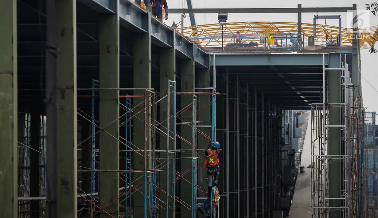 Sejumlah pekerja menyelesaikan pembangunan stasiun kereta Bandara Soekarno-Hatta di Stasiun Sudirman Baru, Jakarta, Jumat (19/5). (Liputan6.com/Faizal Fanani)
