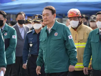 Presiden Korea Selatan Yoon Suk-yeol (tengah) mengunjungi lokasi di mana ratusan orang tewas dan terluka di Seoul, Minggu (30/10/20220). Korban tewas dalam insiden Halloween di Itaewon, Korea Selatan bertambah menjadi 151 orang, demikian laporan dari BBC. (AP Photo/Lee Jin-man)