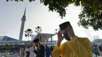 Umat Muslim yang mengenakan masker untuk meredam penyebaran wabah virus corona melaksanakan sholat Idul Fitri menandai akhir bulan suci Ramadhan di luar Masjid Nasional di Kuala Lumpur, Malaysia, Kamis (13/5/2021). (AP Photo/Vincent Thian)