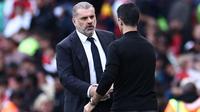 Pelatih kepala Tottenham Hotspur keturunan Yunani-Australia, Ange Postecoglou (kiri), berjabat tangan dengan manajer Arsenal asal Spanyol, Mikel Arteta (kanan), setelah pertandingan Premier League antara Arsenal dan Tottenham Hotspur di Stadion Emirates, London, pada 24 September 2023. Pertandingan berakhir dengan skor 2-2. (HENRY NICHOLLS /AFP)