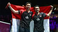 Ganda Putra Indonesia Hendra Setiawan (kiri) dan Mohammad Ahsan membawa bendera Merah Putih usai memenangi babak final Kejuaraan Dunia Bulu Tangkis 2019 di St. Jakobshalle, Basel, Swiss, Minggu (25/8/2019). Ganda Putra Indonesia menang 25-23, 9-21, 21-15 atas ganda Jepang. (FABRICE COFFRINI/AFP)