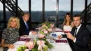 Presiden AS Donald Trump dan Melania Trump duduk bersama Presiden Prancis Emmanuel Macron dan Brigitte Macron dalam jamuan makan malam di Menara Eifel, Paris, Kamis (13/7). Kunjungan Trump ke Paris, merupakan undangan Macron. (AP Photo/Carolyn Kaster)