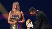 Heidi Klum (kiri) dan pelatih Timnas Argentina, Lionel Scaloni (kanan), meletakkan trofi Piala Dunia sebagai simbolisme bahwa drawing atau undian fase grup Piala Dunia 2026 akan dimulai. (Mandel Ngan/Pool Photo via AP)