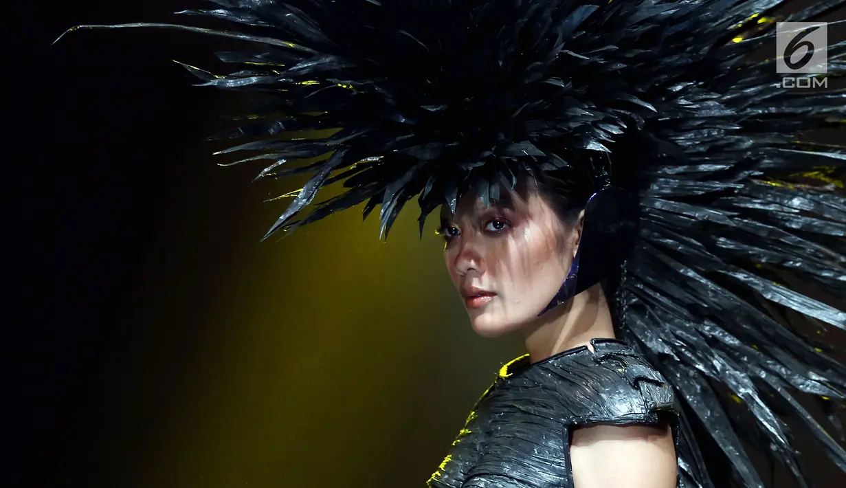 Model membawakan headpiece dan kostum rancangan Rinaldy A. Yunardi pada peragaan tunggal 'Equilibrium' di Jakarta, Rabu (13/12). Dalam pembuatan koleksinya, Rinaldy memanfaatkan bahan seperti jerami hingga plastik daur ulang. (Liputan6.com/Johan Tallo)