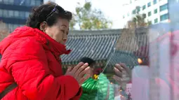 Seorang wanita berdoa untuk keberhasilan anak dan kerabatnya dalam mengikuti tes kemampuan Skolastik College tahunan di Seoul (23/11). Ujian masuk perguruan tinggi ini sebelumnya tertunda akibat gempa yang mengguncang Korsel. (AFP Photo/Jung Yeon-Je)