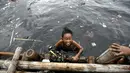 Ekspresi seorang anak saat bermain air di pantai penuh sampah yang terbawa arus di Muara Angke, Jakarta, Rabu (10/2). Genangan sampah yang terbawa arus oleh angin musim barat ini tak menyurutkan anak-anak untuk bermain air. (Liputan6.com/Faizal Fanani)