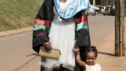 Seorang wisudati membawa anaknya untuk mengikuti upacara wisuda ke-68 di Universitas Makerere di Kampala, Uganda (19/1). Upacara wisuda tersebut diikuti lebih dari 14.000 mahasiswa. (AFP Photo/Michele Sibiloni)