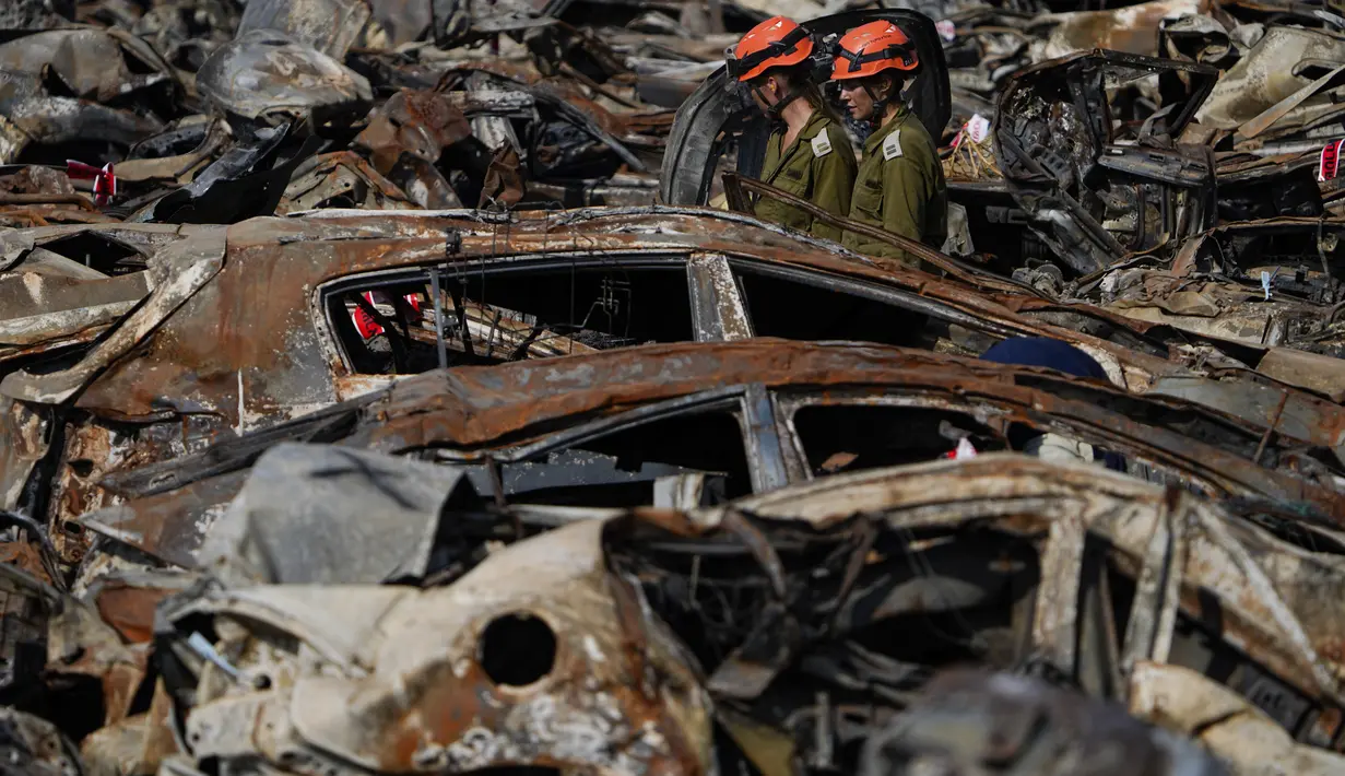 Pasukan keamanan Israel memeriksa kendaraan hangus yang terbakar dalam serangan berdarah lintas perbatasan pada 7 Oktober oleh militan Hamas, di luar kota Netivot, Israel selatan, Rabu (1/11/2023). (AP Photo/Ariel Schalit)