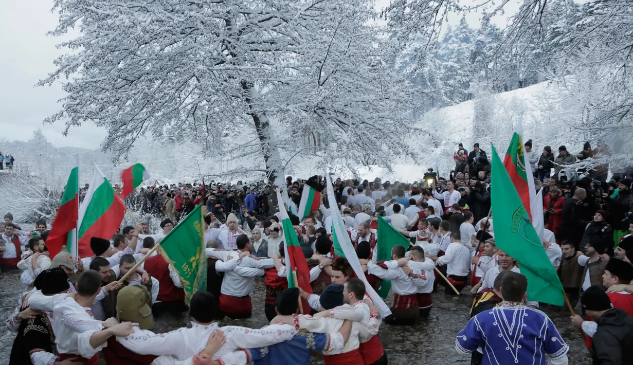  Sejumlah pria Bulgaria menari bersama di perairan sungai Tundzha selama perayaan Hari Epiphany di kota Kalofer, Bulgaria (6/1). Ritual ini dianggap sebagai salah satu cara untuk membersihkan diri dari segala dosa. (AP Photo/Valentina Petrova)