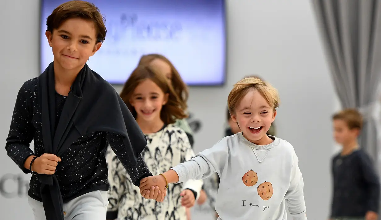 Seorang anak laki-laki dengan down syndrome berjalan di atas catwalk selama pekan mode Petite Fashion Week di Madrid, 6 Oktober 2017. Penampilan dan gaya model mungil  yang menggemaskan dan ekspresif itu mencuri perhatian penonton. (GABRIEL BOUYS/AFP)