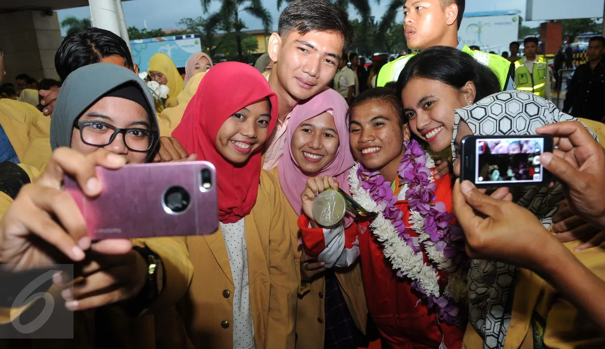 Peraih medali perak angkat besi Olimpiade Rio 2016, Sri Wahyuni Agustiani,saat selfie bersama teman mahasiswa Universitas Bhayangkara Jaya, di Terminal 2 Bandara Soetta, Banten, Minggu (14/08). (Liputan6.com/Helmi Afandi)