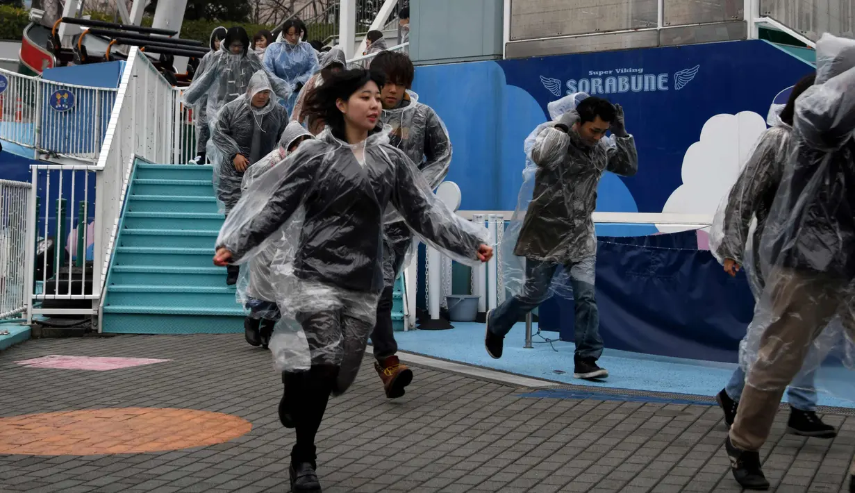 Sejumlah peserta memakai mantel plastik saat mengikuti simulasi evakuasi anti-rudal di taman hiburan Tokyo Dome City, Jepang, (22/1). Di tengah balistik Korea Utara, warga Jepang menggelar simulasi evakuasi anti-rudal. (AFP Photo/Toshifumi Kitamura)