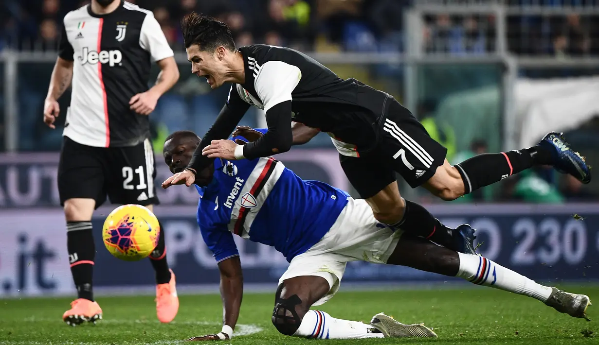 Striker Juventus, Cristiano Ronaldo, terjatuh saat berebut bola dengan bek Sampdoria, Omar Colley pada laga Serie A 2019 di Stadion Luigi Ferraris, Rabu (18/12). Juventus menang 2-1 atas Sampdoria. (AFP/Marco Bertorello)