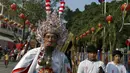 Seorang pria mengenakan kostum unik dengan kail tajam yang menembus pipinya dalam acara Hei Neak Ta atau parade roh untuk memperingati Cap Go Meh, Kamboja, (21/2). Cap Go Meh merupakan rangkaian acara dari tahun baru Imlek. (REUTERS/Samrang Pring) 	