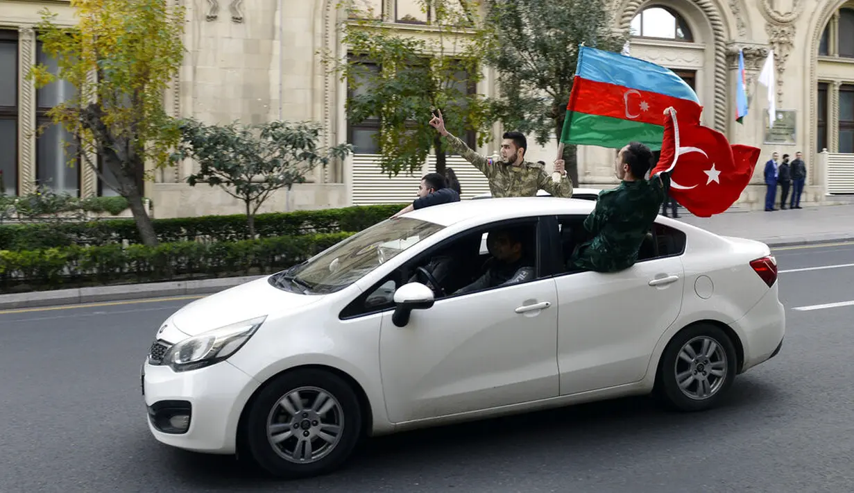 Rakyat Azerbaijan mengibarkan bendera nasional dan Turki di Baku, Azerbaijan, Selasa (10/11/2020). Armenia dan Azerbaijan mengumumkan perjanjian damai untuk menghentikan pertempuran atas wilayah Nagorno-Karabakh di Azerbaijan berdasarkan pakta yang ditandatangani dengan Rusia. (AP Photo)