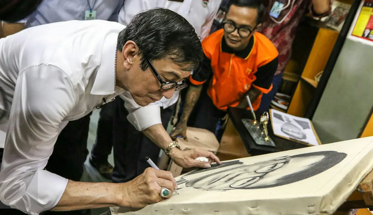 Menteri Hukum dan HAM, Yasonna Laoly menandatangani lukisan dirinya saat mengunjungi LP Salemba, Jakarta, Rabu (9/3/2016). Kunjungan Menkumham tersebut untuk mengontrol peredaran narkotika di dalam Lapas. (Liputan6.com/Yoppy Renato)