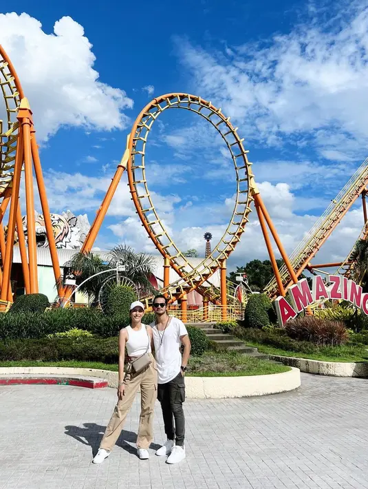 Mengunjungi Siam Amazing Park, Tyas tampil stylish dengan tank top, jogger pants dan sneakers. Begitu pun Tengku yang mengenakan kaus warna senada dengan Tyas. [Instagram/tyasmirasih]