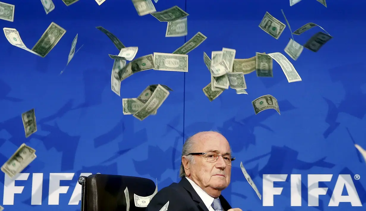 Presiden FIFA, Sepp Blatter terdiam saat uang kertas dilemparkan kepada dirinya saat tiba untuk konferensi pers usai Rapat Luar Biasa Komite Eksekutif FIFA di markas FIFA di Zurich, Swiss (20/7/2015). (REUTERS/Arnd Wiegmann)
