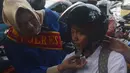 Personel Polisi Wanita (Polwan) Polres Jakarta Timur yang mengenakan busana kebaya, membantu mengenakan helm kepada penggendara motor ketika mengatur arus lalu lintas di Jalan Otista Raya, Jatinegara, Jakarta, Jumat (20/4). (Merdeka.com/Imam Buhori)