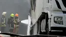 Petugas memadamkan sebuah truk yang terbakar akibat tertimpa pesawat kecil yang jatuh dekat pasar swalayan daerah permukiman di Tires, Portugal, Senin (17/4). Akibat insiden tersebut, beberapa mobil lain dan rumah disekitarnya terbakar. (andre nobre/AFP)