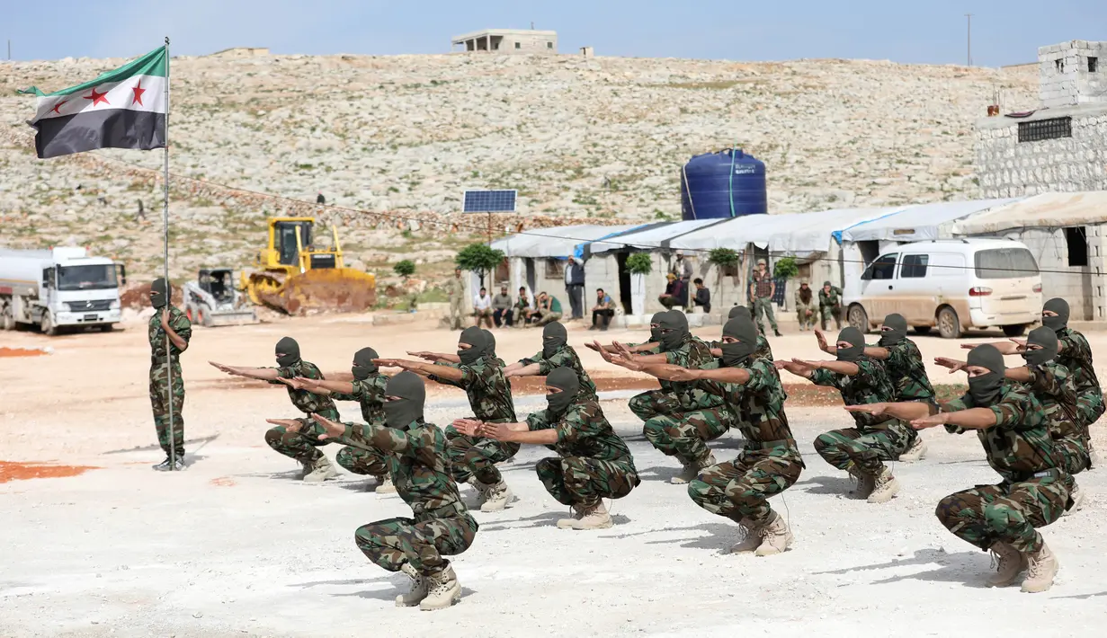 Pejuang dari Jaysh al-Izza (the Army of Glory) membentuk barisan saat melakukan latihan di kota Idlib, Suriah (9/4). Pejuang Jaysh al-Izza ini adalah afiliasi dari tentara Suriah yang didukung oleh Turki. (AFP/Omar Haj Kadour)