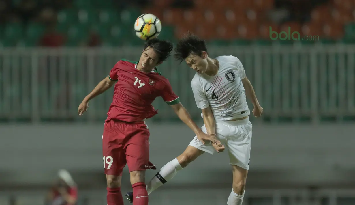 Duel pemain Timnas Indonesia U-23, Hanif Syahbandi (kiri) dengan pemain Korea Selatan U-23, Lee Seung-mo pada laga uji coba di Stadion Pakansari, Bogor, (23/6/2018).  Indonesia U-23 kalah 1-2 dari Korea U-23. (Bola.com/Nick Hanoatubun)