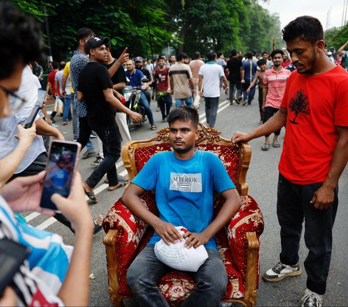 Seorang pengunjuk rasa duduk di sebuah sofa yang dijarah dari Ganabhaban, rumah Perdana Menteri Bangladesh, di Dhaka, Bangladesh, pada 5 Agustus 2024. Pengunjuk rasa menyerbu kediaman PM Bangladesh yang mewah dengan menjarah berbagai perabotan dan TV.&nbsp; R