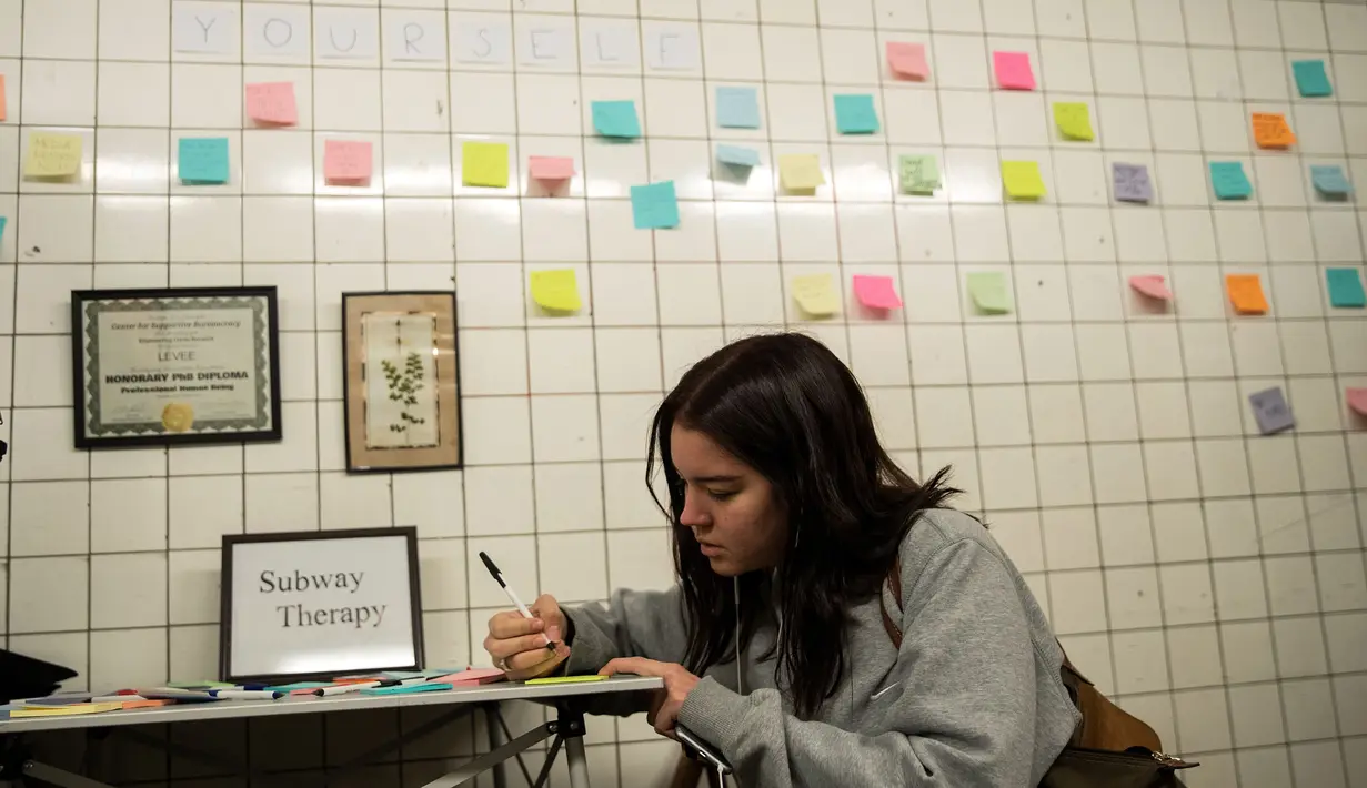 Alma Berti menulis pesan di selembar post-it sebagai bagian dari 'subway therapy' di dinding stasiun Union Square, New York, Kamis (10/11). Kegiatan ini menjadi semacam terapi bagi warga yang ingin melepaskan emosi mereka. (DREW ANGERER/AFP)