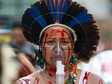 Seorang perempuan Brasil mengenakan masker oksigen portabel dalam aksi unjuk rasa menuntut keadilan iklim dan menentang kebakaran hutan yang melanda seluruh negeri di Sao Paulo, Brasil, pada tanggal 22 September 2024. (Miguel SCHINCARIOL/AFP)