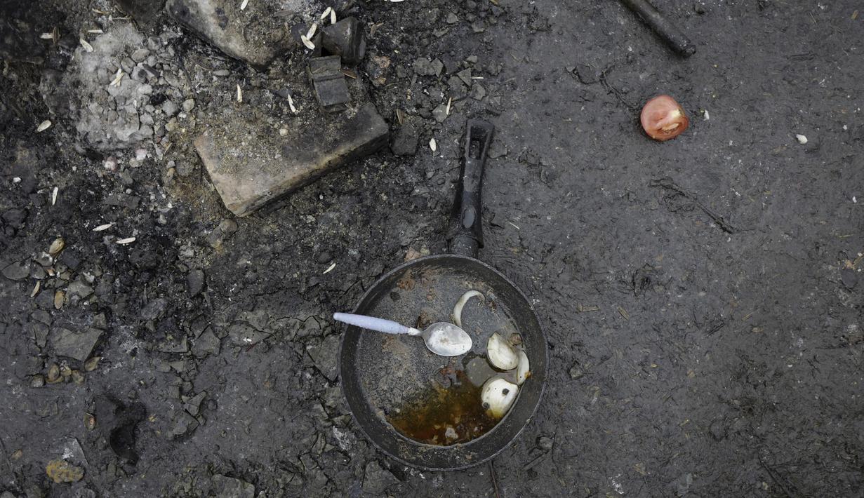 Sebuah panci tergeletak di lantai di sebuah kamp darurat di Calais, Prancis utara, Sabtu (27/11/2021). Di kamp-kamp darurat di luar Calais, para migran yang putus asa menunggu kesempatan untuk mencoba menyeberangi Selat Inggris. (AP Photo/Rafael Yaghobzadeh)