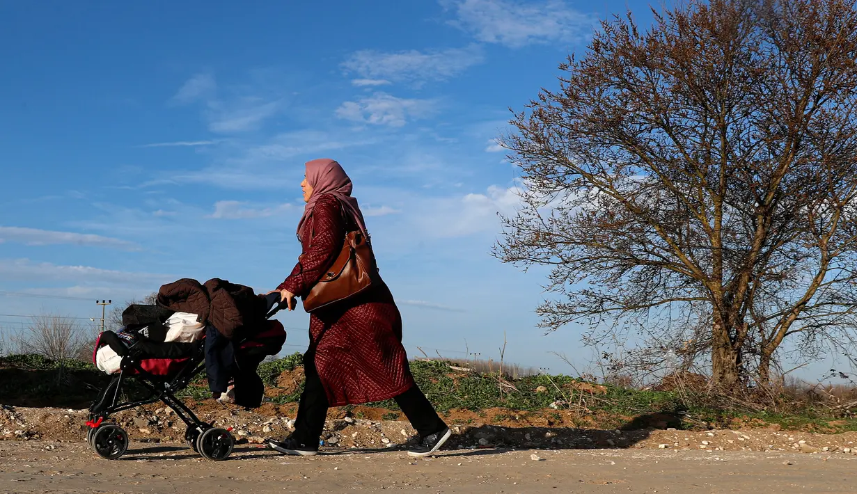 Seorang wanita migran mendorong kereta bayi dalam perjalanan menuju perbatasan Turki dengan Yunani di Pazarkule, Turki, Selasa (3/3/2020). (AP Photo/Darko Bandic)