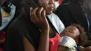 Seorang wisudati membawa anaknya saat mengikuti upacara wisuda ke-68 di Universitas Makerere di Kampala, Uganda (19/1). Sebanyak lebih dari 14.000 mahasiswa menerima gelar dari Universitas Makerere. (AFP Photo/Michele Sibiloni)