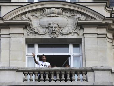 Bintang sepak bola Argentina, Lionel Messi melambaikan tangan kepada para fans dari balkon hotelnya di Paris, Selasa (10/8/2021). Lionel Messi telah mencapai kesepakatan dengan Paris Saint-Germain (PSG) mengenai kepindahan ke klub Prancis tersebut. (AP Photo/Adrienne Surprenant)