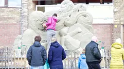 Sejumlah warga menyaksikan seorang seniman yang sedang memahat patung pasir dalam Kompetisi Memahat Pasir Eropa di Zandvoort, Belanda, pada 15 Oktober 2020. (Xinhua/Sylvia Lederer)
