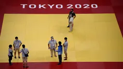 Para juri, relawan, dan teknisi bekerja di dalam venue Nippon Budokan untuk pertandingan judo dan karate selama Olimpiade Tokyo 2020 di Tokyo pada 21 Juli 2021. (AFP/Franck Fife)