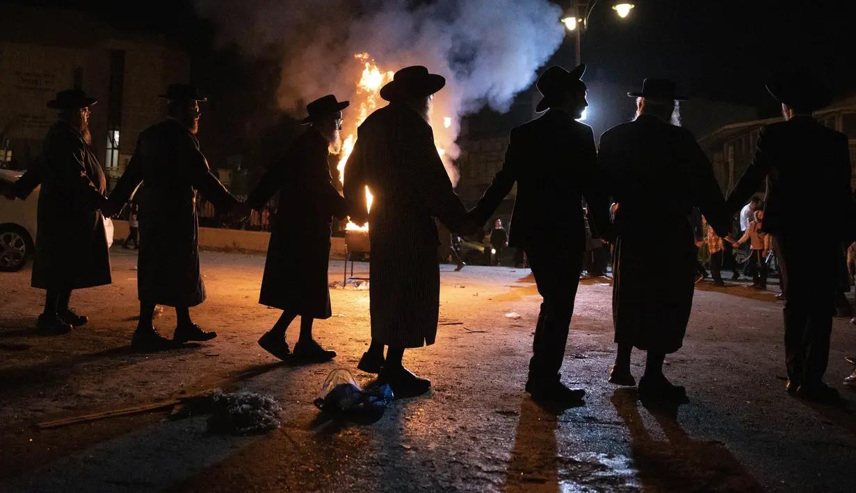Pria Ultra-Ortodoks Yahudi menari di samping api unggun di Yerusalem, Kamis (29/4/2021). Selama liburan Lag Ba'Omer, menandai berakhirnya wabah yang dikatakan telah membinasakan orang Yahudi selama zaman Romawi. (AP Photo/Sebastian Scheiner)