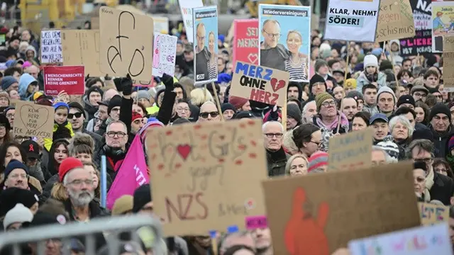 Para pengunjuk rasa memegang poster berdiri di depan Reichstag (gedung parlemen Jerman) di Berlin selama demonstrasi pada Minggu, (2/2/2025).