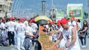 Tahap akhir pembuatan pizza sepanjang 1 mil untuk pecahkan rekor dunia di pinggir Laut Naples, Italia, 18 Mei 2016. Pizza terpanjang itu dibuat menggunakan 2.000 kg tepung, 1.6000 kg tomat, 2.000 kg mozzarella dan 200 liter minyak. (Mario LAPORTA/AFP)