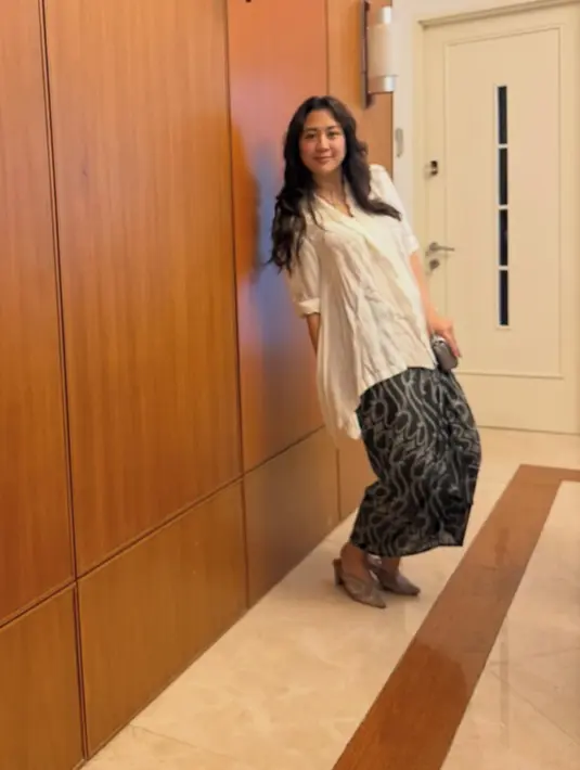 Sherina mengenakan atasan kebaya loose modern putih dipadukan bawahan kain hitam yang memiliki corak warna putih. [@sherinamunaf]