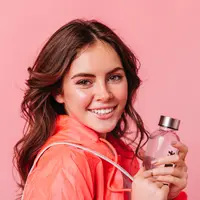 Seorang perempuan sedang menggenggam sebuah botol parfum (Foto Dok: Freepik/lookstudio).
