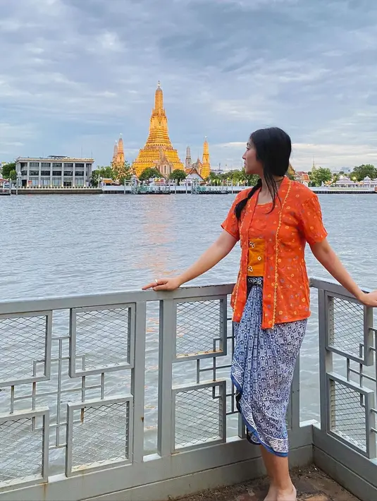 Kebaya pendek warna orange dengan kain lilit biru untuk outfit jalan-jalan. [Instagram/febbyrastanty]