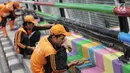 Pasukan oranye atau PPSU melakukan pengecatan jembatan layang dengan warna-warna ceria di Kampung Makasar, Jakarta, Kamis (26/7).  Pengecatan dilakukan guna mempercantik dan menyambut Asian Games 2018 pada Agustus mendatang.  (Liputan6.com/Faizal Fanani)