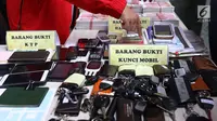 Petugas menunjukkan barang bukti saat rilis kasus pemalsuan dokumen dan uang palsu di Jakarta, Rabu (20/12). Bareskrim Polri menangkap sebanyak 13 tersangka yang mulai beroperasi sejak 2014 di wilayah Jakarta dan Jawa Barat. (Liputan6.com/Angga Yuniar)