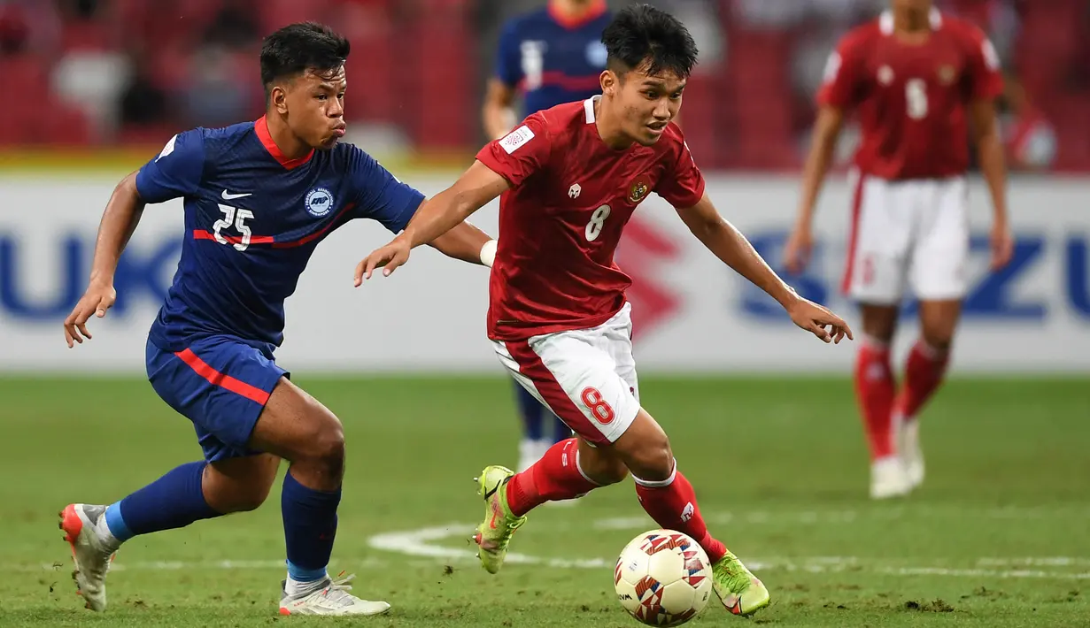 Pemain Singapura Nur Adam Abdullah (kiri) berusaha merebut bola dari pemain Indonesia, Witan Sulaeman pada pertandingan leg kedua semifinal Piala AFF 2020 di National Stadium, Sabtu (25/12/2021). Laga dimenangkan Indonesia 4-2 lewat perpanjangan waktu 2 x 15 menit. (AFP/Roslan Rahman)