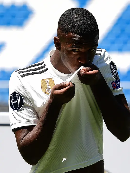 Penyerang baru Real Madrid, Vinicius Junior mencium logo klub selama presentasi resmi dirinya di Stadion Santiago Bernabeu, Madrid (20/7). Vinicius sudah direkrut Madrid pada bursa transfer musim panas 2017. (AFP Photo/Pierre-Philippe Marcou)