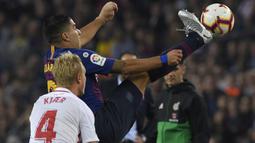 Striker Barcelona, Luis Suarez, berebut bola dengan bek Sevilla Simon Kjaer, pada laga La Liga Spanyol di Stadion Camp Nou, Barcelona, Sabtu (20/10). Barcelona menang 4-2 atas Sevilla. (AFP/Lluis Gene)